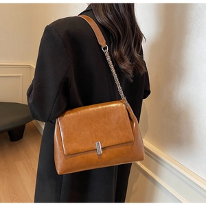 Detailed view of a brown vintage leather shoulder bag with a silver metallic rectangular lock