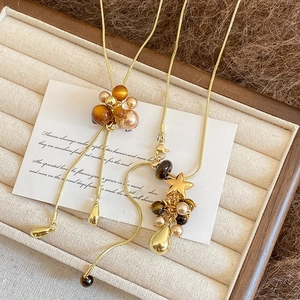 Detail einer langen Pulloverkette mit Perlen und Tigerauge-Anhängern auf Goldkette