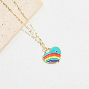 Detailed macro shot of a gold necklace featuring a vibrant rainbow enamel heart pendant