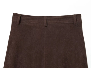 Détail de la texture en daim marron foncé et passants de ceinture sur la jupe