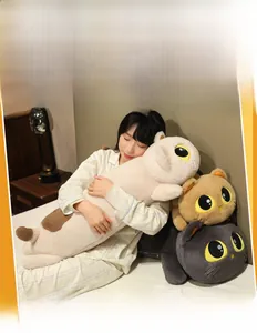 Three long plush cat pillows in beige, brown and grey shown in a cozy bedroom scene