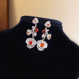 Gros plan de boucles d'oreilles fleuries avec zircons et pierres orange sur velours