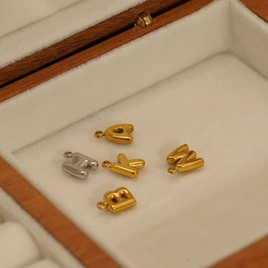 Detail of 3D bubble letter pendants in gold and silver plating on white velvet lining