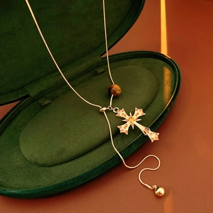 Tiger eye stone cross pendant on gold snake chain inside a green velvet jewelry box