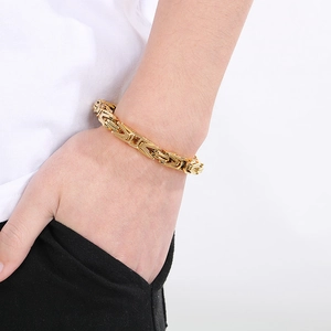 Macro detail of men's gold Byzantine link chain bracelet with a heavy metallic texture
