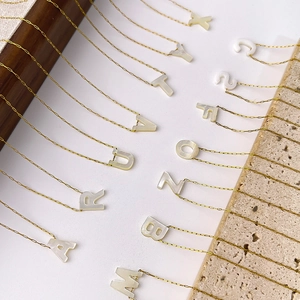 Vue macro de pendentifs lettres dorés avec incrustation de nacre sur une chaîne fine