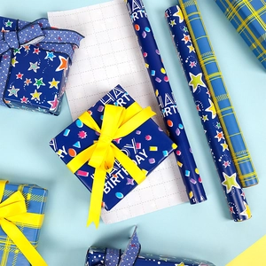 Close-up of blue Happy Birthday wrapping paper rolls and matching gift ribbons