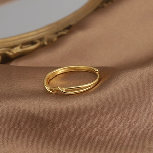 Macro shot of minimalist twisted golden ring on premium brown silk fabric background