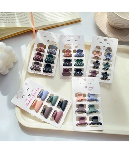 Close-up of mini flower hair claws in Morandi colors on a cat-themed display card