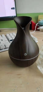 Detail of dark wood grain vase humidifier on a desktop with touch power button