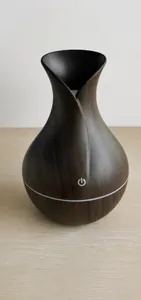 Detail of dark wood grain vase humidifier on a desktop with touch power button