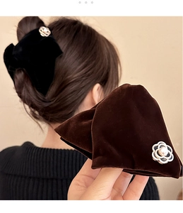 Detail of velvet bow hair claw with pearl camellia flower and metal trim accent