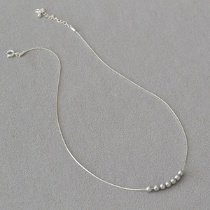 Elegant silver minimalist necklace with seven polished beads on a delicate metal chain