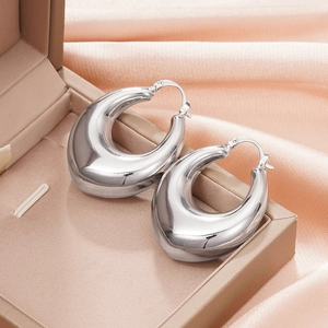 Close-up of polished silver teardrop hoop earrings resting on silk fabric in a gift box