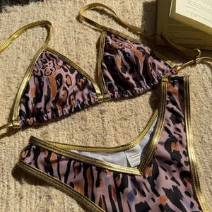 Close-up of leopard print bikini fabric with golden trim and washing label details