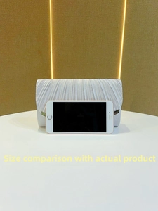 Silver pleated evening clutch bag size comparison with a mobile phone on a white display stand