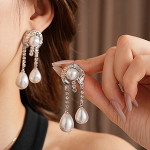 Dettaglio di orecchini a goccia in argento con perle tonde e catene di strass su modella