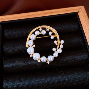 Detailed macro shot of 24k gold plated round pearl brooch on black velvet display