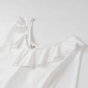 Détail d'une robe en satin blanc avec encolure à volants et fines bretelles à nouer