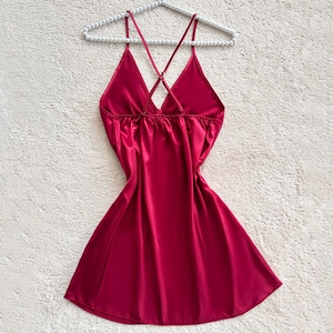 Elegant deep red satin nightdress with thin straps and cross-back detail on white fur