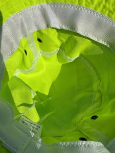 Interior detail of fluorescent green bucket hat with sweatband, seams and cotton care label