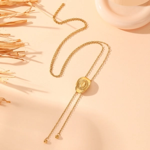 Detailed view of golden bolo tie necklace with shield pendant and metallic spheres
