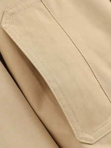 Macro shot of khaki trench coat showing premium twill cotton fabric and precise stitching