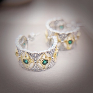 Detail of vintage two-tone earrings with emerald green stone and pave white diamonds