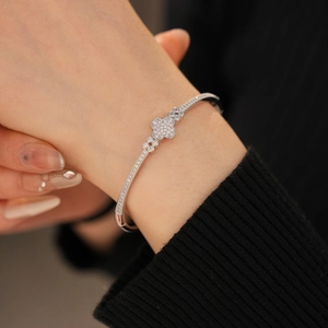 Close-up of a silver clover bracelet with pavé-set zircons worn on a model's wrist