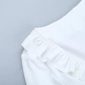 Détail du haut en tricot blanc montrant les volants et la texture côtelée fine