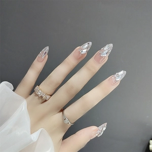 Close-up of long stiletto press-on nails with silver glitter and irregular rhinestones