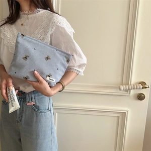 Blue corduroy bag held by hand featuring cute bear embroidery and heart patterns