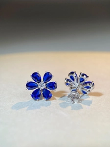 Macro shot of S925 silver daisy earrings with blue pear-cut stones and silver butterfly back