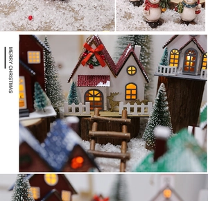 Close-up of LED glowing wooden Christmas house with miniature snowman and snowy trees