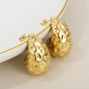 Macro detail of golden 18K gold plated stainless steel teardrop earrings with hammered texture