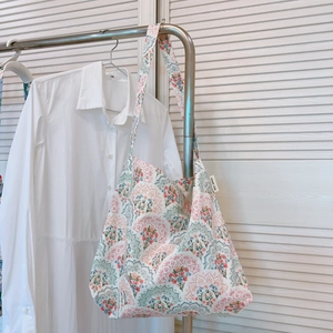 Dettaglio della borsa tote con mandala floreale appesa su uno sfondo di persiane bianche