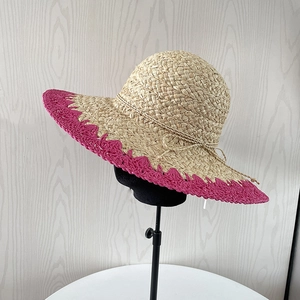 Détail d'un chapeau de soleil en raphia tressé main avec bord festonné magenta et nœud
