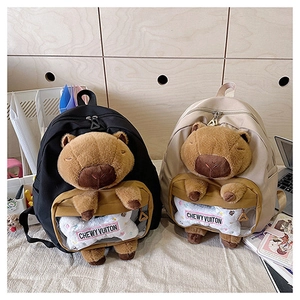 Detail of Capybara backpacks in black and beige with plush charms and transparent pockets