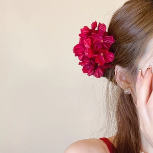 Detailed view of a large burgundy fabric flower hair clip on a woman's hair
