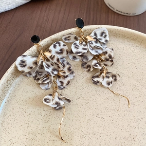 Close-up of leopard print fabric flower earrings with long tassels on a ceramic plate