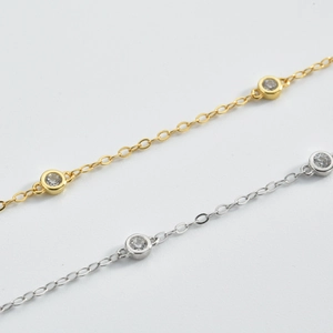 Detailed view of silver and gold chain necklaces with round bezel-set cubic zirconia stones