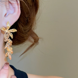 Gros plan de boucles d'oreilles fleurs en cristal champagne avec pampilles ambrées