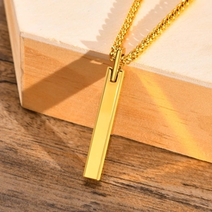 Close-up of golden rectangular bar pendant with twist chain on minimalist wood base