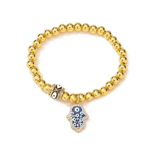 Detailed view of gold beaded elastic bracelet with Hamsa Hand and Evil Eye charms