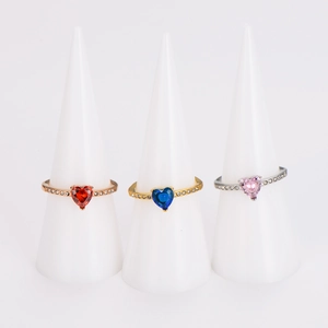 Three heart-shaped gemstone rings in gold and silver finish on white jewelry displays