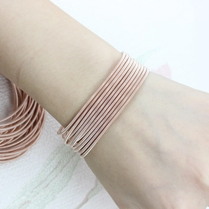 Close-up of a stacked rose gold guitar string spring bracelet on a woman's wrist