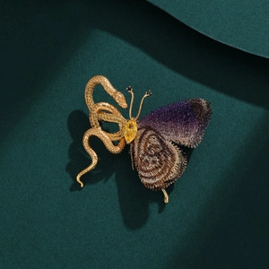Detail of snake brooch with purple embroidered butterfly wings and yellow gemstone inlay