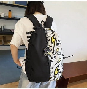 Detail of black and white backpack with lightning print and astronaut charm on model