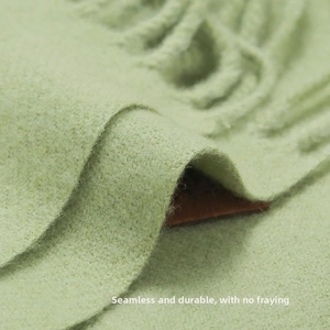 Detail of light green cashmere-feel scarf showing thick texture and integrated hem stitching
