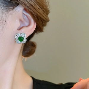Detailed view of silver flower earrings with emerald green stone and sparkling zircons